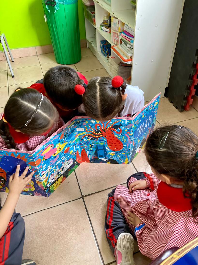 Niños de pre-básica explorando un libro ilustrado